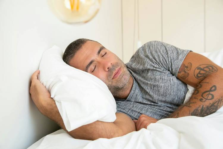a man with tattoos on his arm is sleeping in bed