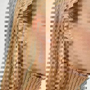 a close up of a woman wearing a pair of stud earrings