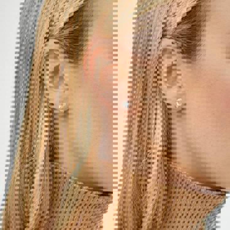 a close up of a woman wearing a pair of stud earrings