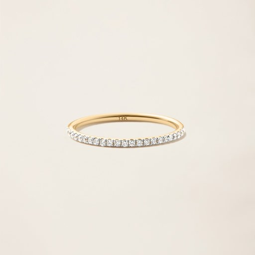 a yellow gold ring with a row of diamonds on a white surface