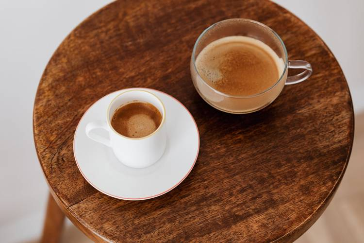 two cups of coffee are on a wooden table