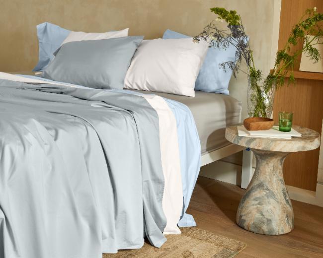 Sateen sheets on a bed next to a bedtime table