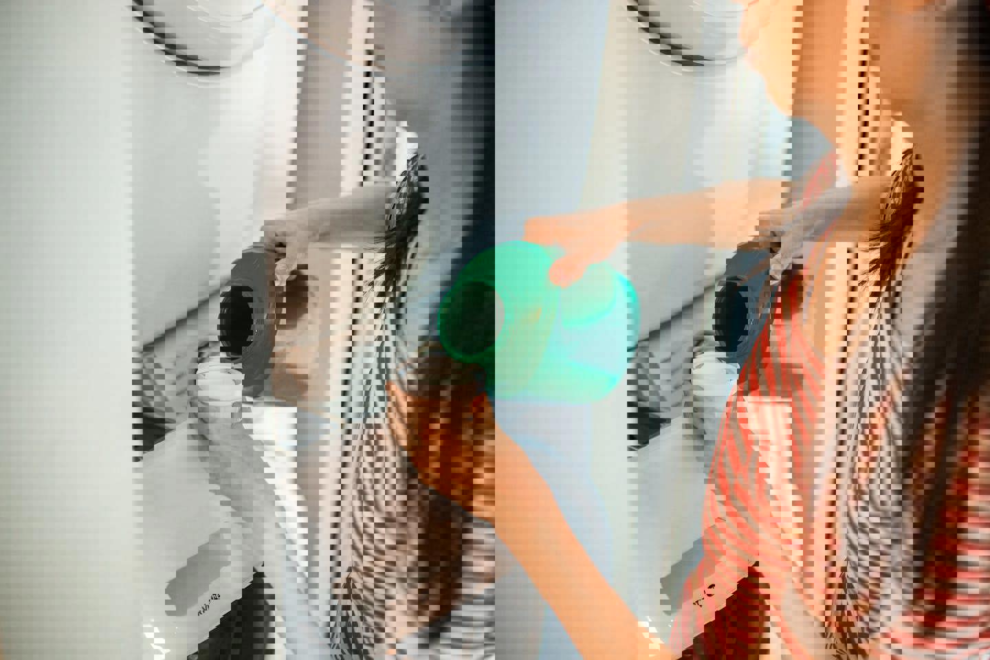 a woman is pouring laundry detergent into a washing machine