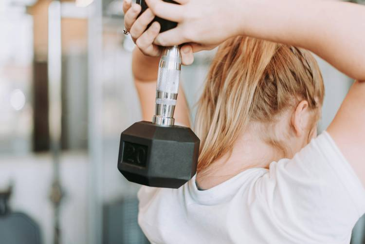 a woman is lifting a dumbbell with the number 20 on it