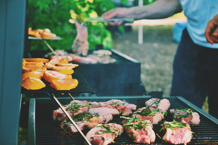a man is cooking meat and vegetables on a grill