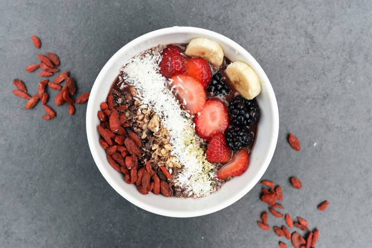 a bowl of food with berries and coconut on top