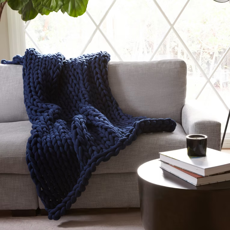 a blue knitted blanket is laying on a grey couch