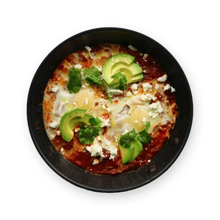 a bowl of food with eggs , avocado , cheese and cilantro on a black background