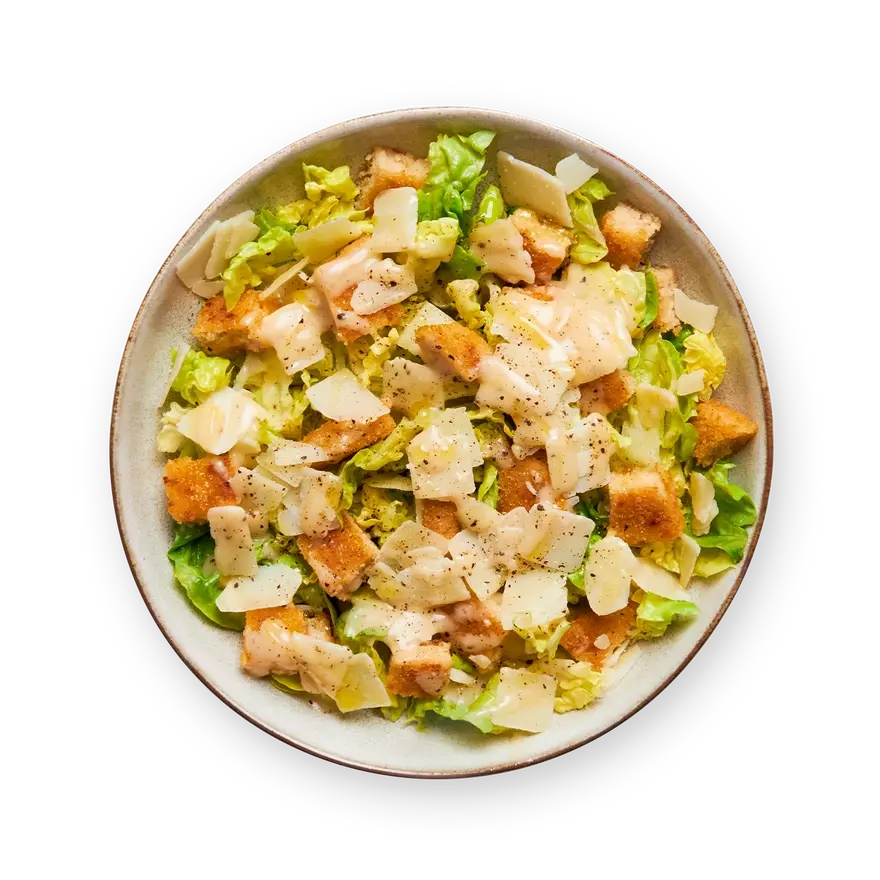 a close up of a caesar salad in a bowl on a black background