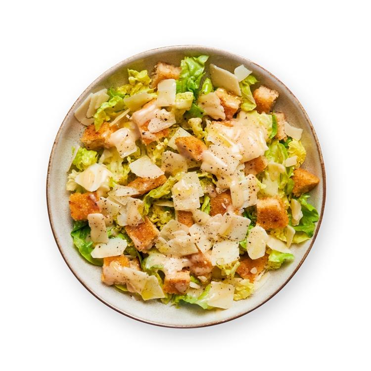 a close up of a caesar salad in a bowl on a black background