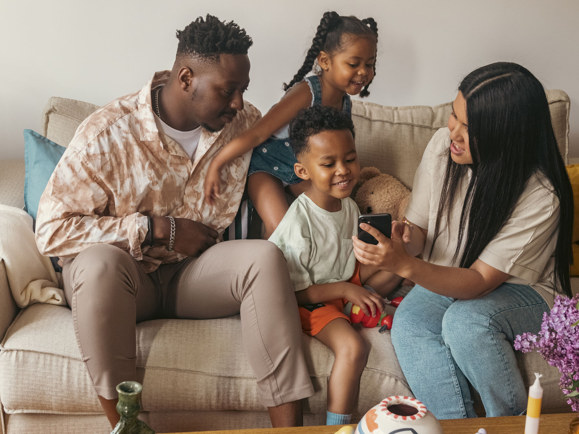 a family is sitting on a couch looking at a cell phone
