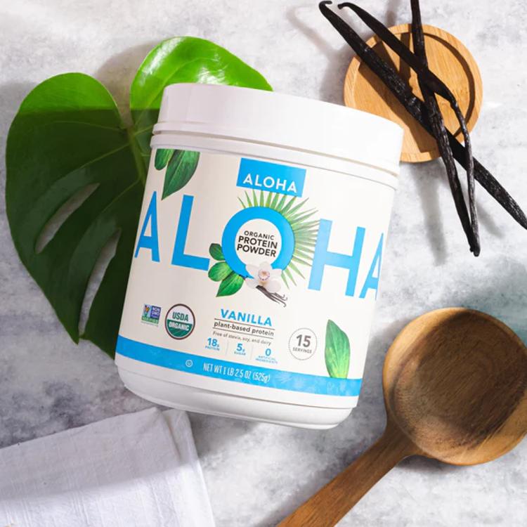 a container of aloha vanilla protein powder next to a wooden spoon