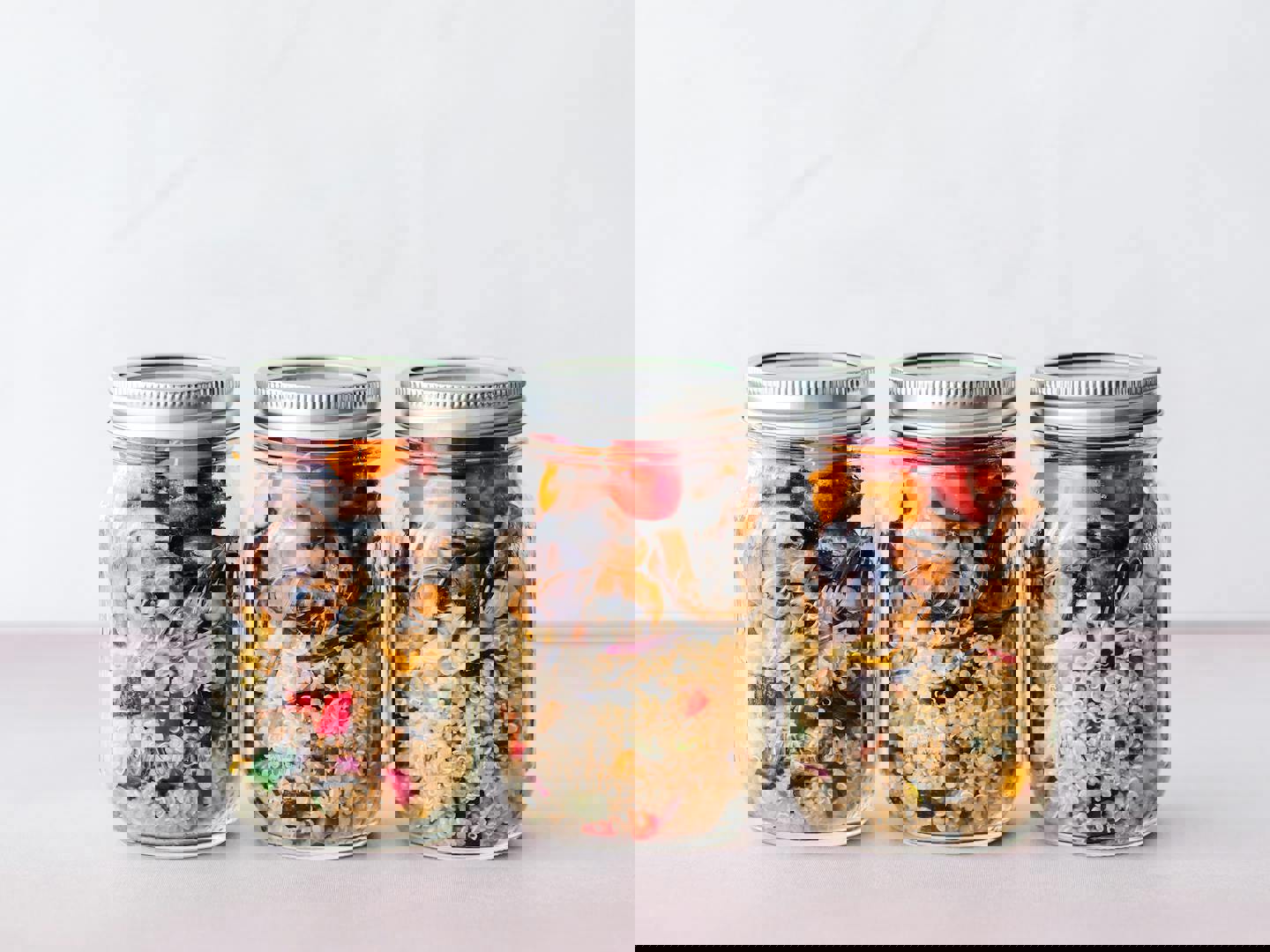 three mason jars filled with rice and vegetables on a table