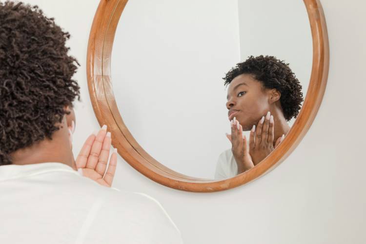 a woman looks at her reflection in a round mirror