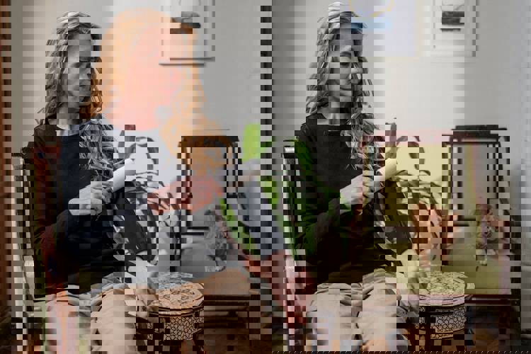 a woman is sitting in a chair cleaning her arm with a lint roller