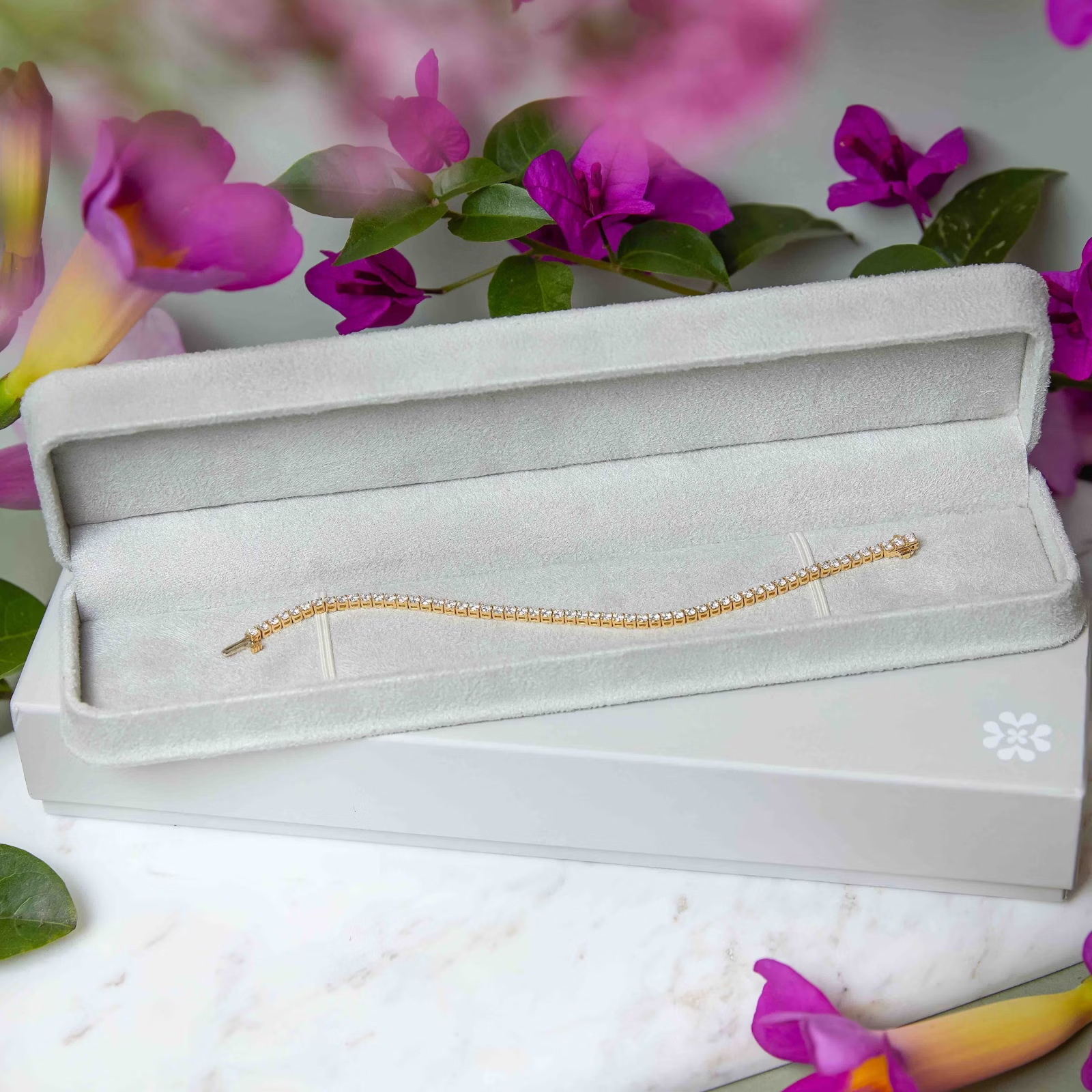 a bracelet is sitting in a box with purple flowers in the background