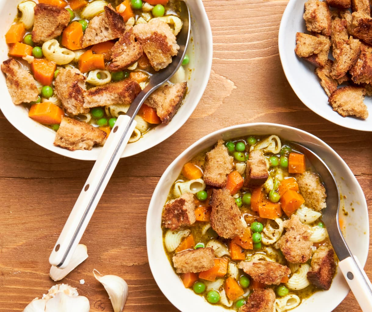 three bowls of soup with croutons and spoons on a wooden table three bowls of soup with croutons and spoons on a wooden table