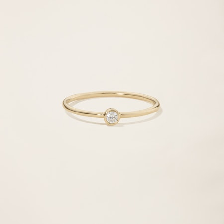 a yellow gold ring with a single diamond in the center