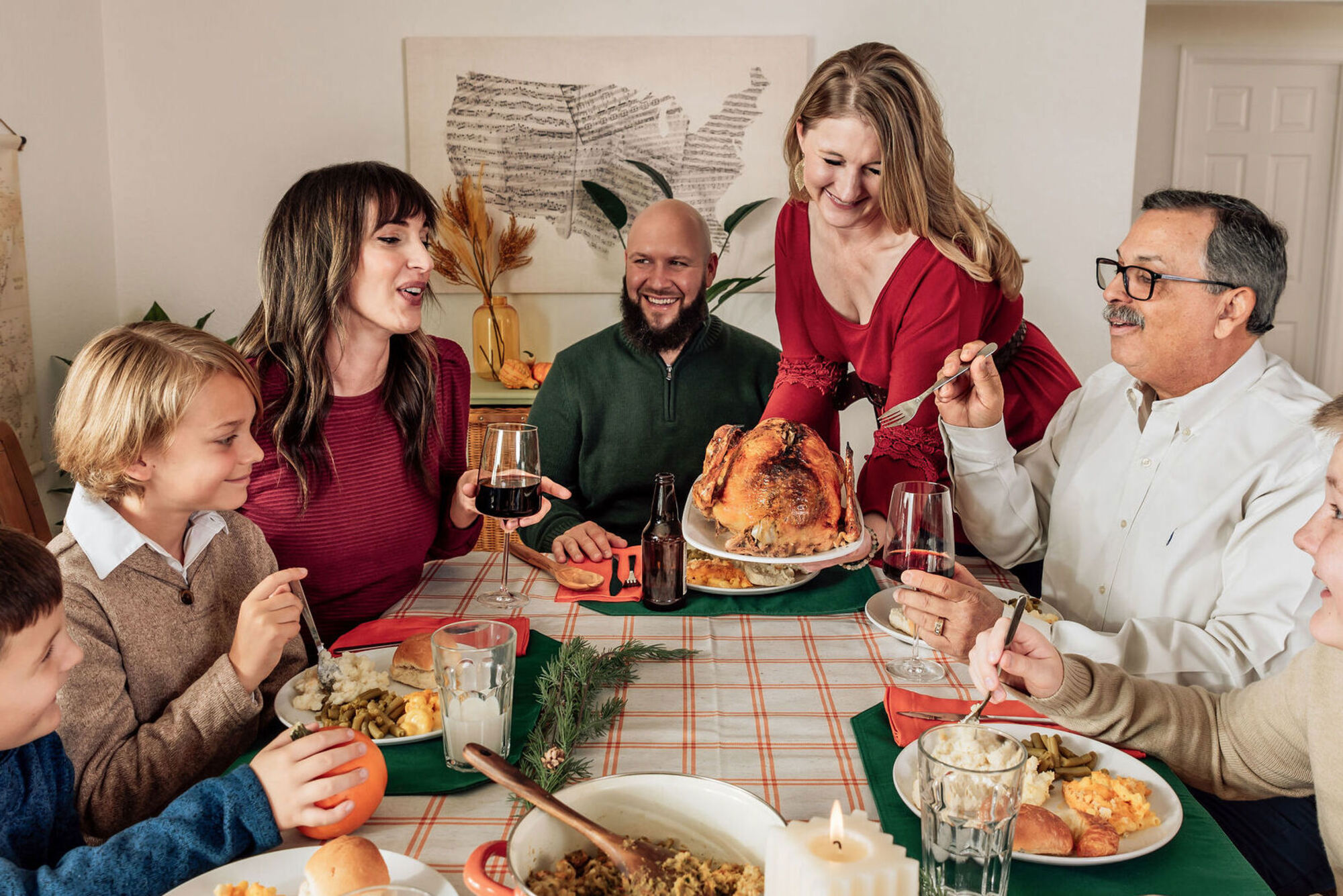 a woman is serving a turkey to a man at a dinner table