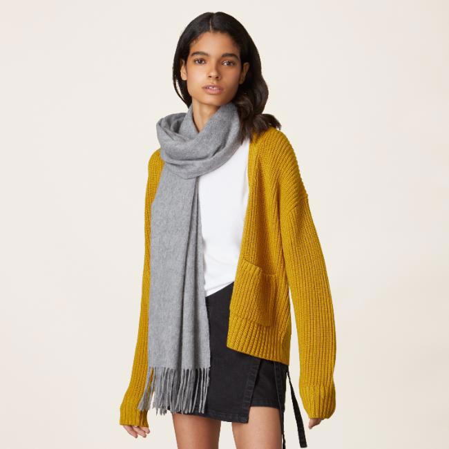 a woman wearing a yellow cardigan and a grey scarf