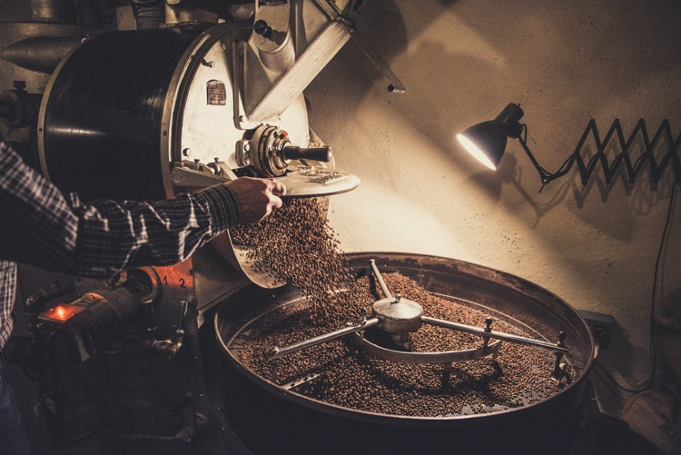 a man is roasting coffee beans in a machine with a label that says ' a ' on it