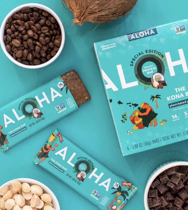 a box of aloha special edition protein bars surrounded by bowls of nuts and coffee beans