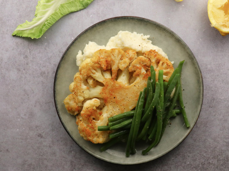 a plate of food with mashed potatoes green beans and cauliflower