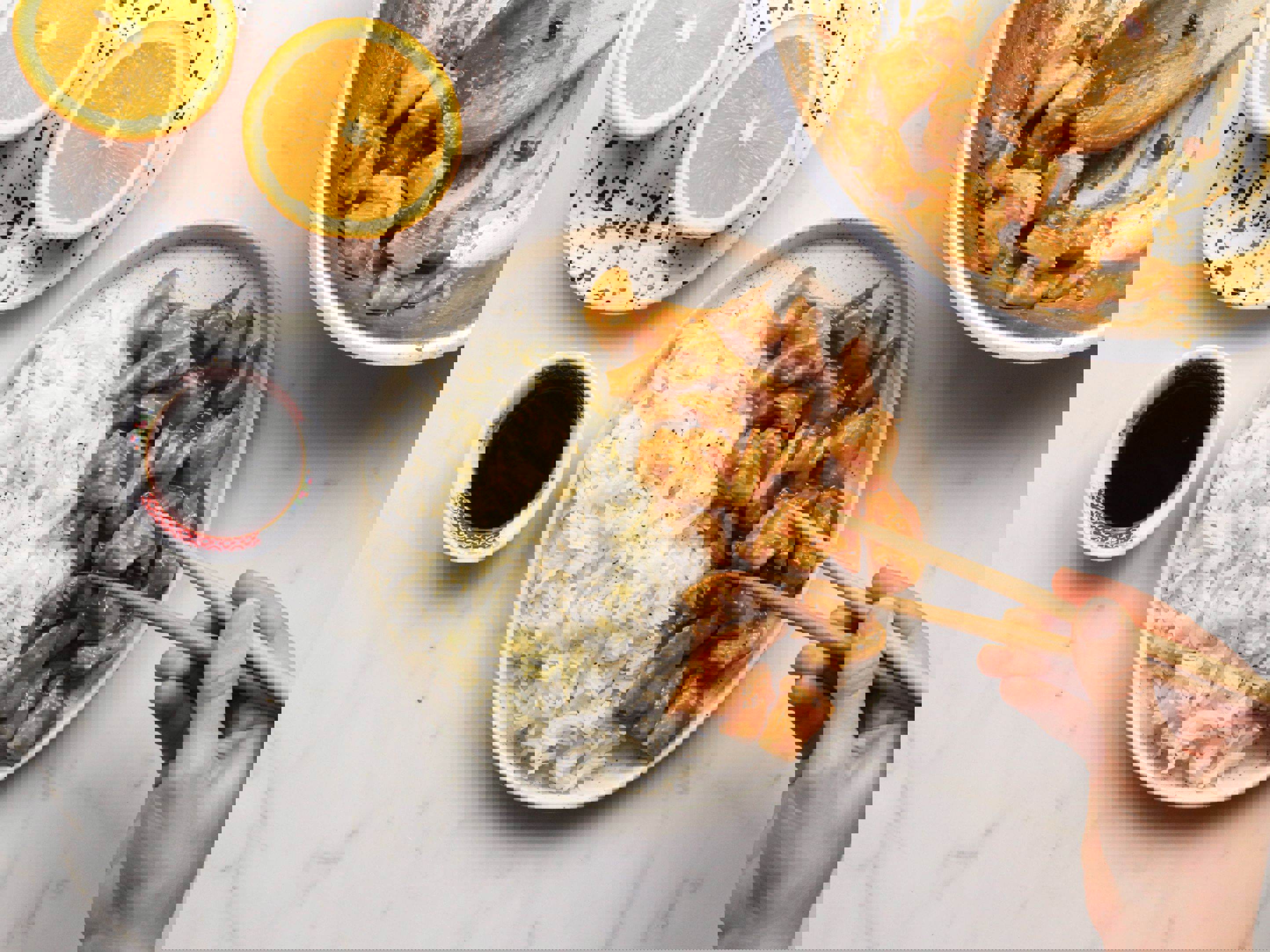 a person is eating chicken and rice with chopsticks