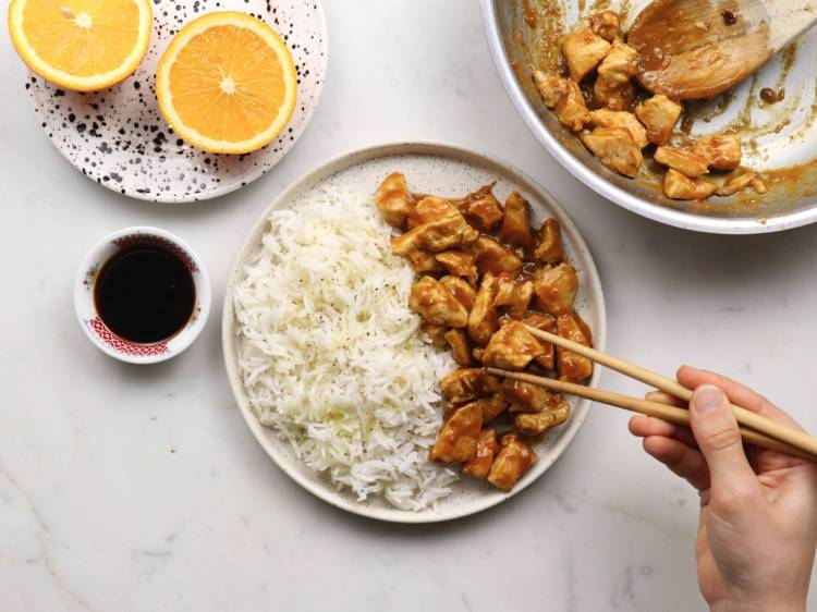 a person is eating chicken and rice with chopsticks