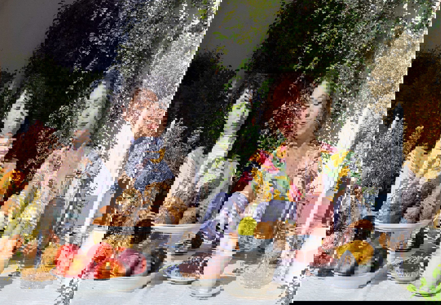 two women sit at a table with food and drinks