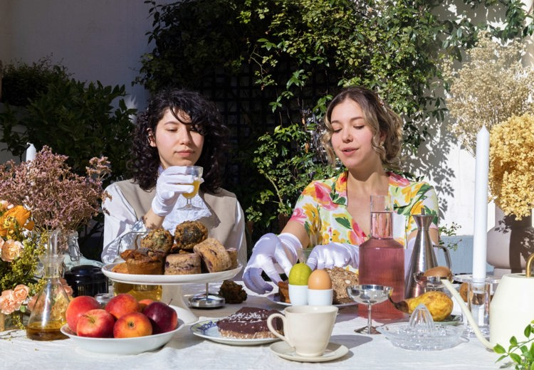 two women sit at a table with food and drinks